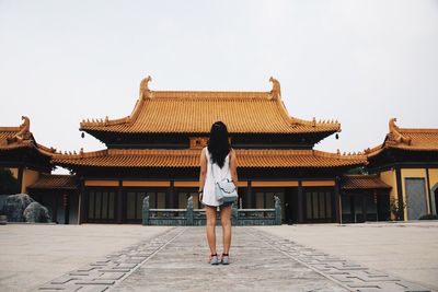 Rear view of woman standing in front of traditional houses