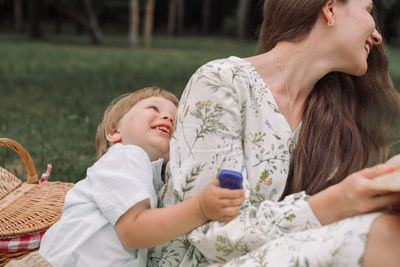 Cute boy and mother enjoying while sitting at park