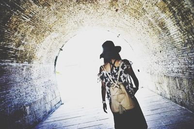 Rear view of backpack woman walking in tunnel