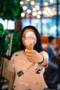 Woman holding ice cream cone in city at night