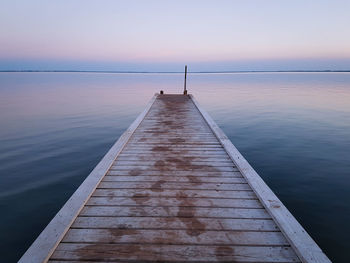 Pier over sea against sky during sunset