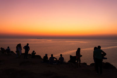 Silhouette people at mountain against horizon during sunset