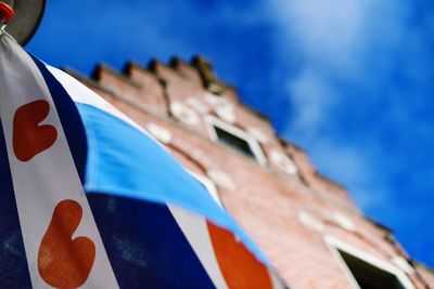 Low angle view of flag against building against blue sky