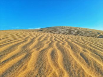 Scenic view of desert against clear blue sky