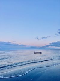 Boat moored on sea against sky during sunset