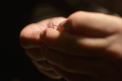 Close-up of person putting thread in needle