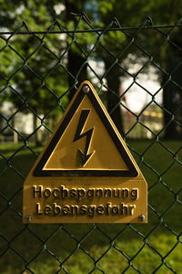 Close-up of information sign on chainlink fence