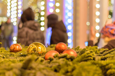 Close-up of christmas ornaments with people standing in background