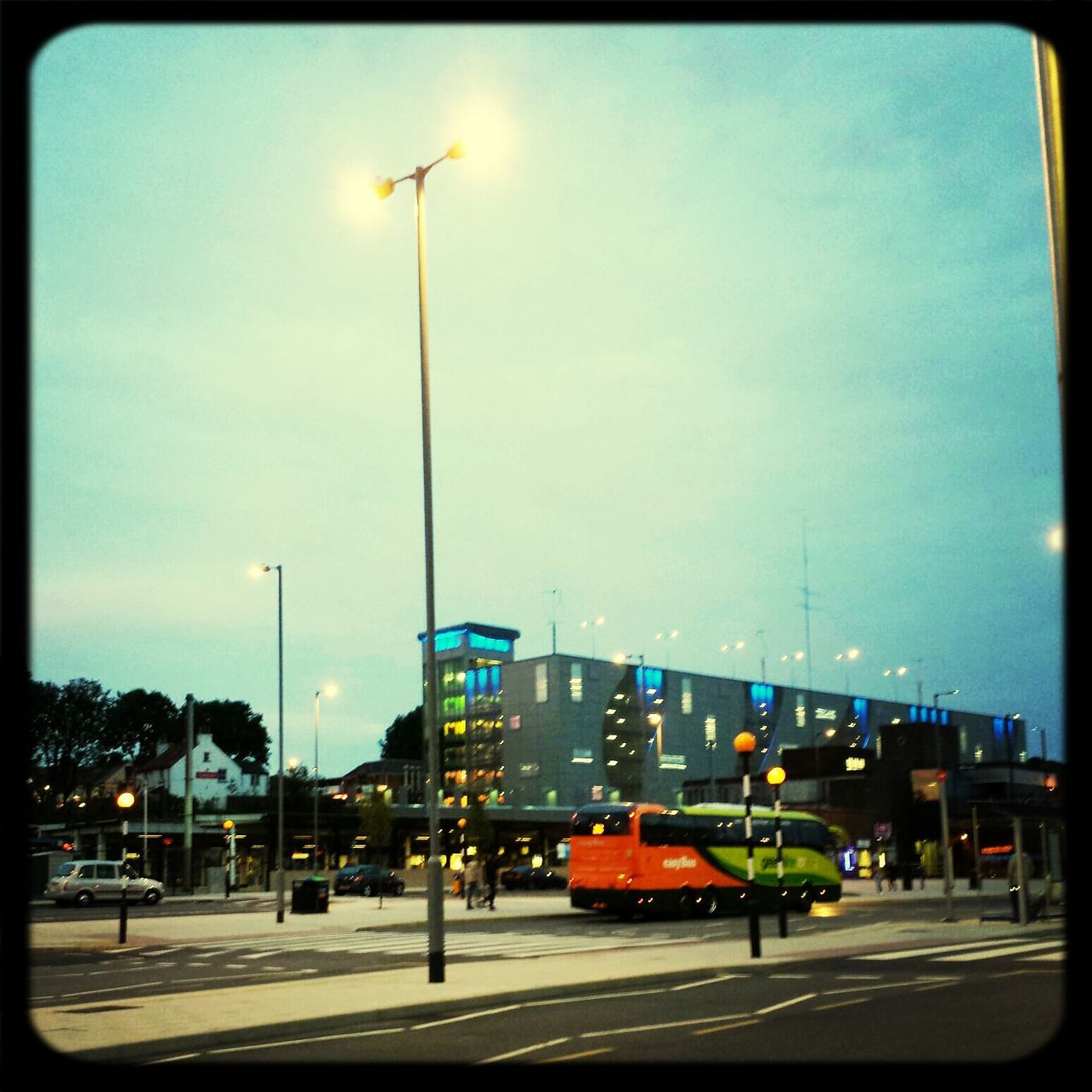 transfer print, street light, transportation, building exterior, sky, car, street, built structure, architecture, city, auto post production filter, mode of transport, road, land vehicle, lighting equipment, illuminated, city street, city life, traffic, road marking