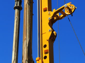 Low angle view of crane against clear blue sky