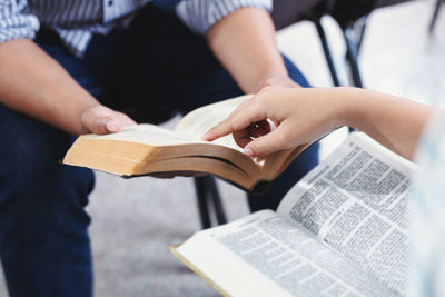 Midsection of woman reading book on paper