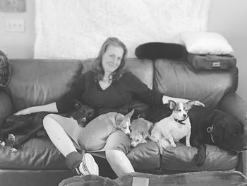 Portrait of woman sitting with dogs on sofa at home