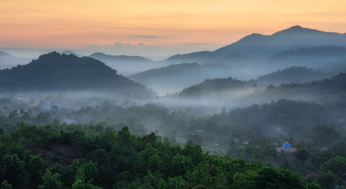 Scenic view of mountains during foggy weather at sunset