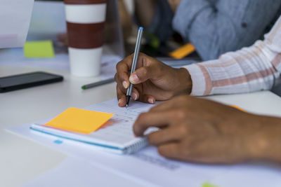 Female entrepreneur writing notes in diary at office