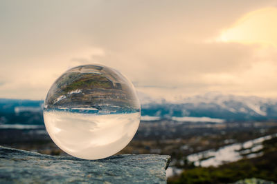Close-up of crystal ball against sky during winter