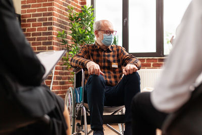 Senior man wearing mask sitting on wheelchair