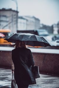 Rear view of woman holding umbrella during winter