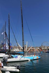 Sailboats moored in harbor against clear blue sky