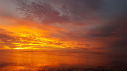 Scenic view of sea against dramatic sky during sunset