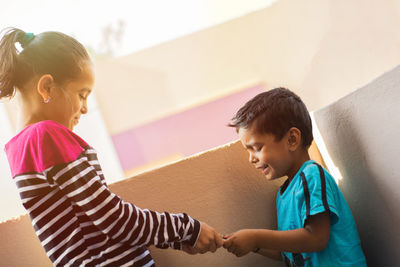 Girl smiling woman with arms raised against wall