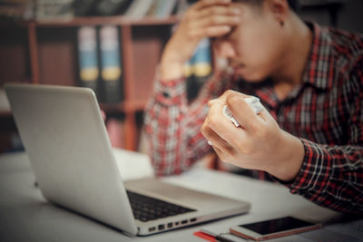Midsection of man using mobile phone while sitting on table