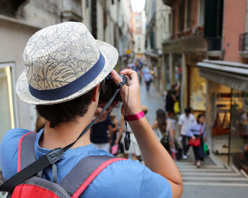 Rear view of woman wearing hat on street in city