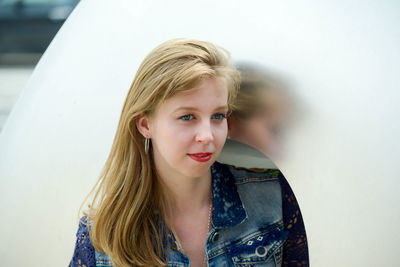 Young woman looking away while standing by metal structure