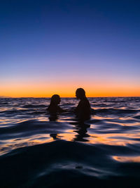 Silhouette people on beach against sky during sunset