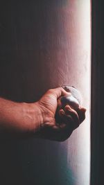 Close-up of hand holding drink against wall