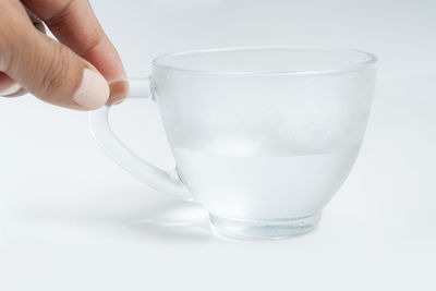 Close-up of hand holding drink against white background