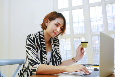 Young woman using mobile phone while sitting in office
