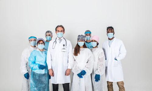 Portrait of doctors wearing mask standing against white background