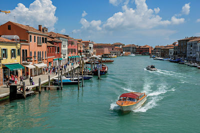 View of buildings, in front of canal with motorboat in murano, a village near venice, italy.