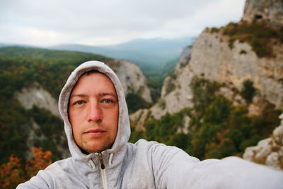 Portrait of man in hooded shirt against mountains