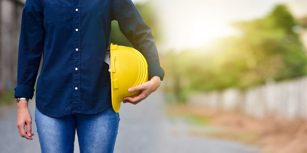 Midsection of woman holding yellow while standing outdoors