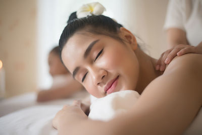 Smiling young woman being massaged on table in spa