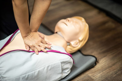 High angle view of person showing cpr over dummy on floor 