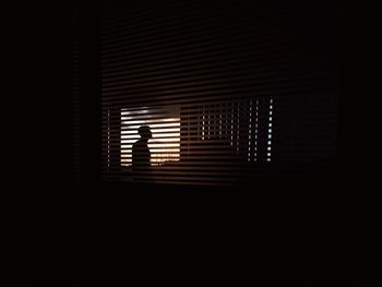 Silhouette man seen through blinds window