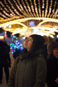 Woman looking up at amusement park during night