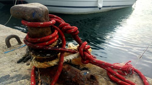 Close-up of rope tied to bollard at harbor