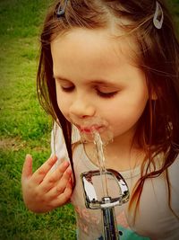 Close-up of cute girl drinking water on fountain at park