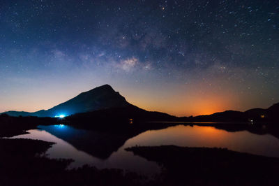 Scenic view of lake and mountains against sky at night