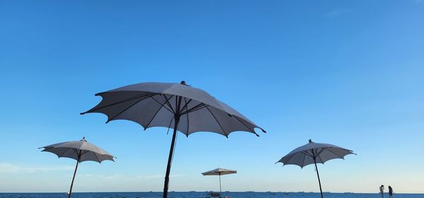 Low angle view of umbrella against clear blue sky