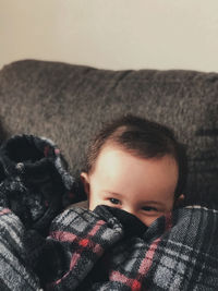 Close-up portrait of cute boy relaxing on bed at home