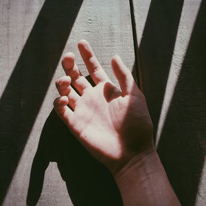 High angle view of person shadow on hand against wall