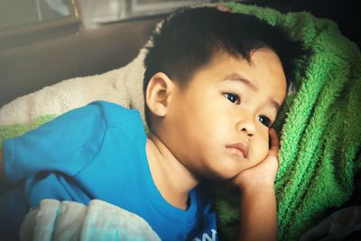 Close-up of thoughtful boy lying on bed at home