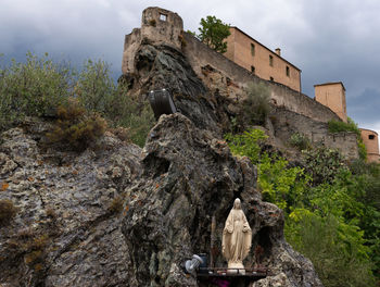 Low angle view of cross on rock against sky