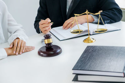 Midsection of man reading book while sitting on table
