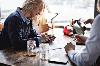 Mature businesswoman working in meeting with coworkers at restaurant