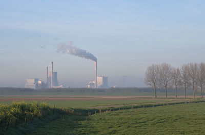 Smoke emitting from factory against sky